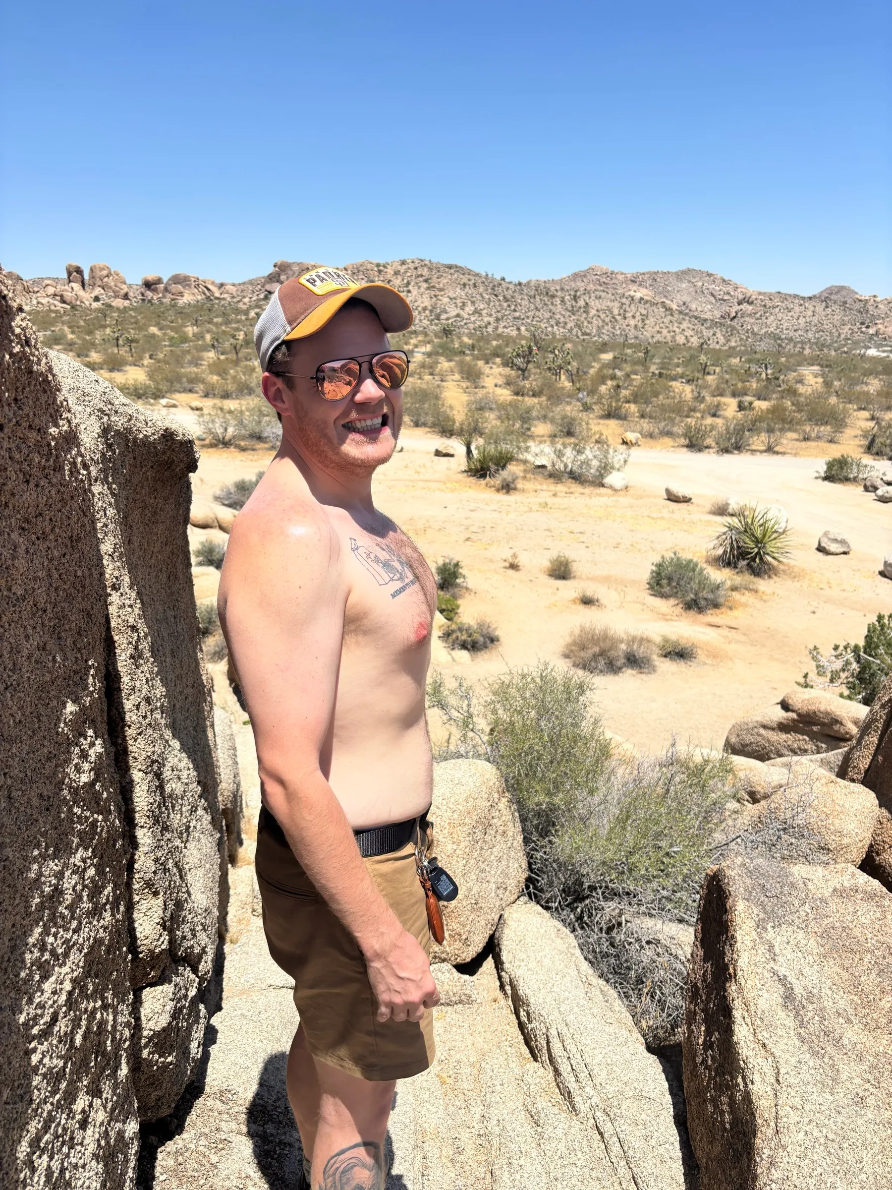 Standing shirtless on the boulders in a Padres hat