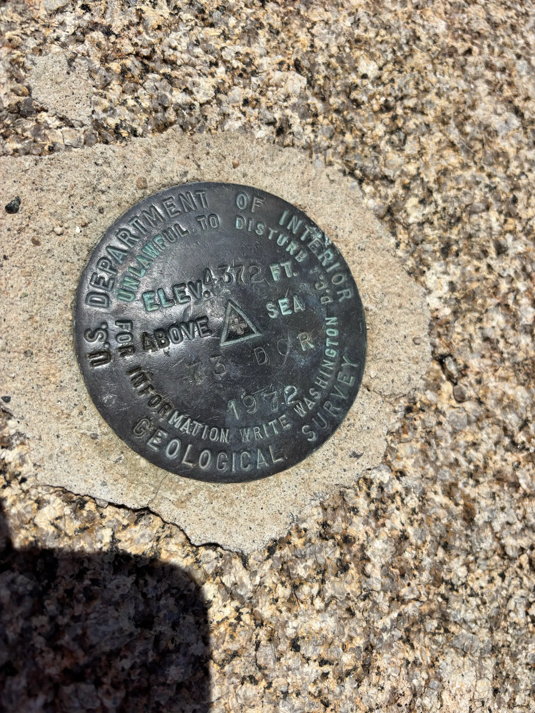 A USGS survey marker embedded in the granite, elevation 4,372 feet
