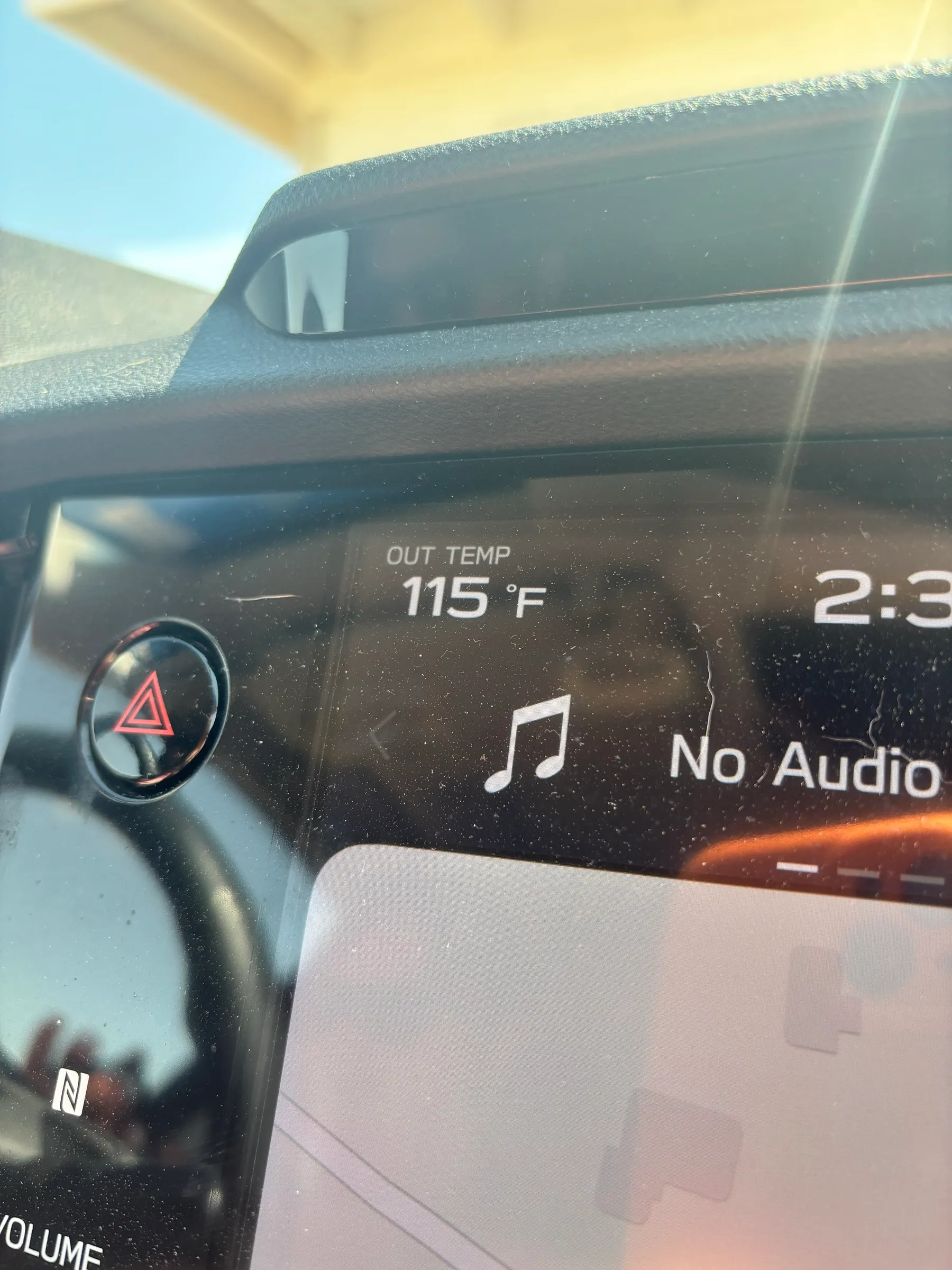 A car dashboard showing an outside temperature of 115 degrees Fahrenheit