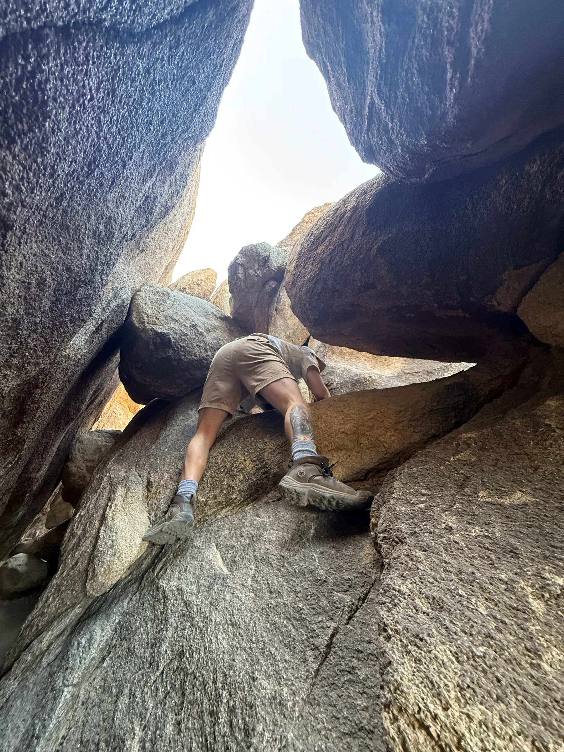 Scrambling up a gap between boulders, shot from below
