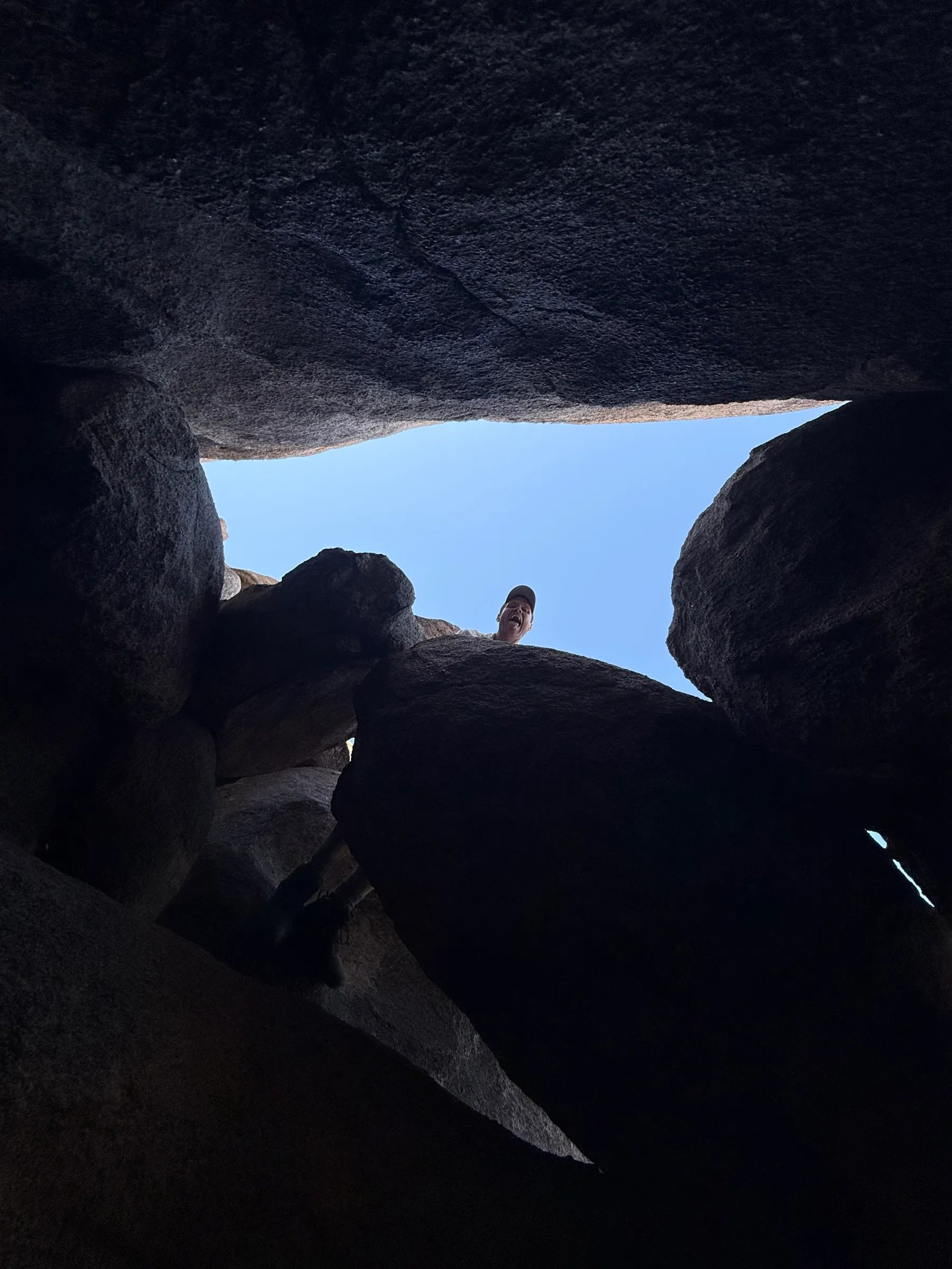 Looking up from inside a boulder cave at someone peering down