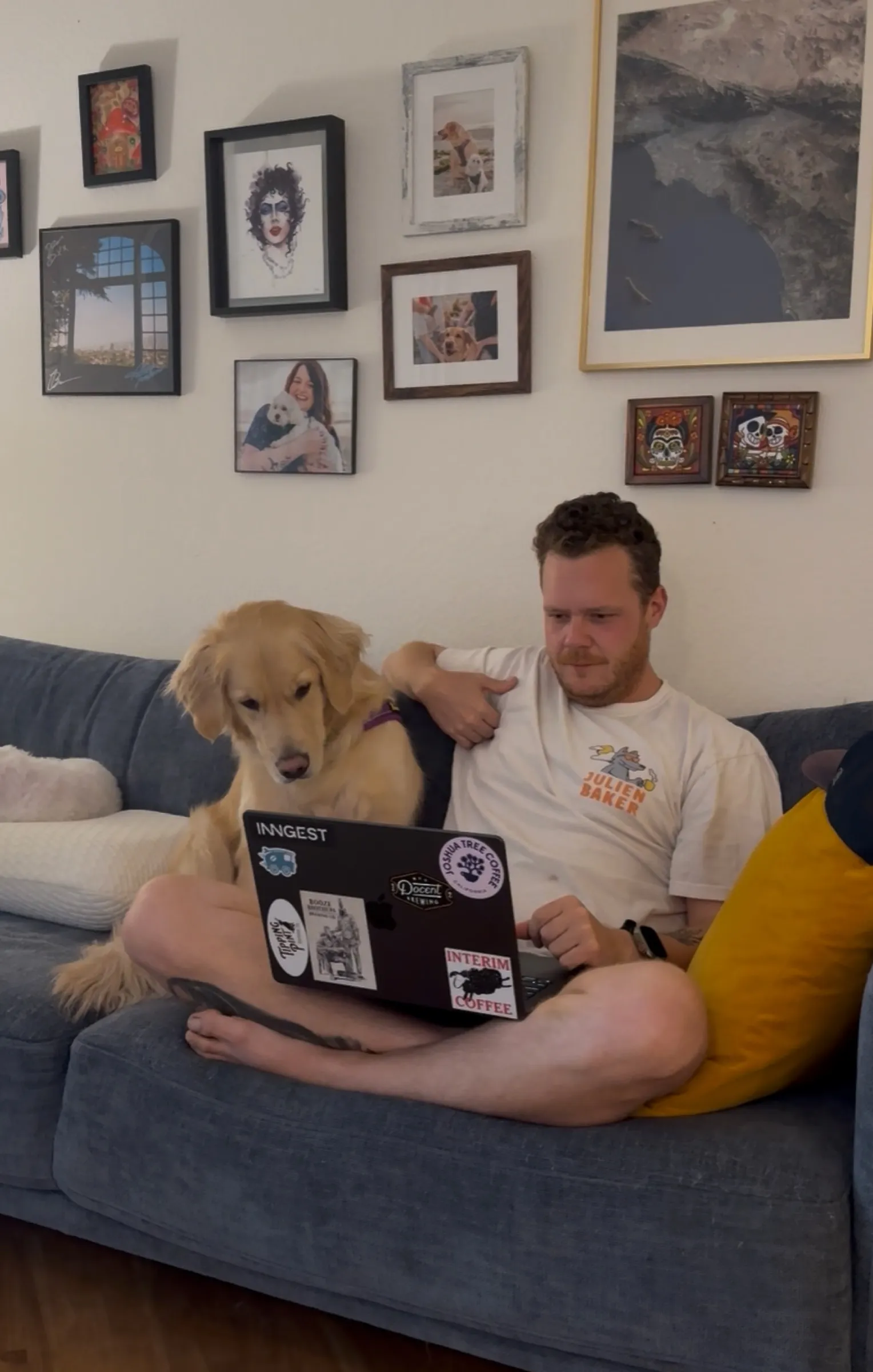 Working from the couch with a stickered laptop while Josie supervises