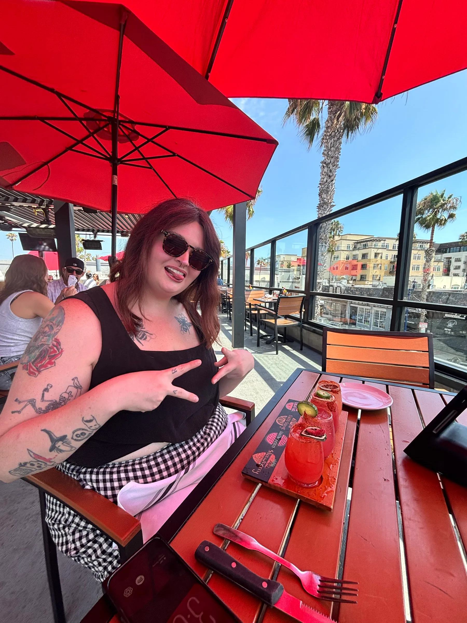 A flight of drinks with chili rims at a rooftop patio with red umbrellas
